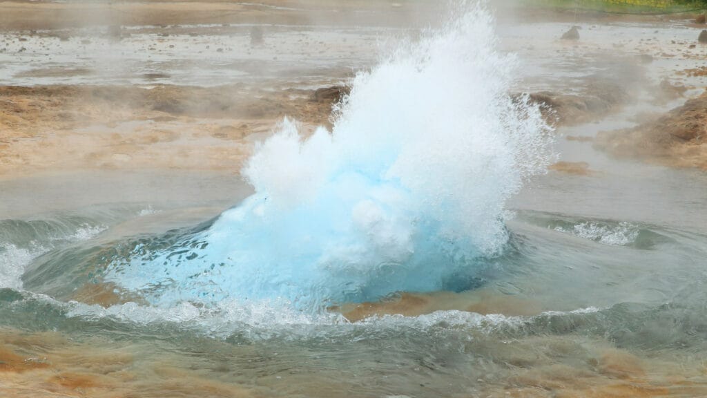 Geothermal geyser erupting with steam and hot water, demonstrating geothermal energy in action