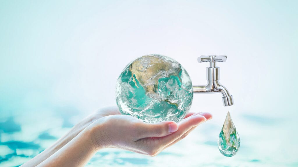 A hand holding a transparent globe with water flowing from a tap into a water drop, symbolizing sustainable water well usage and eco-friendly groundwater resources.